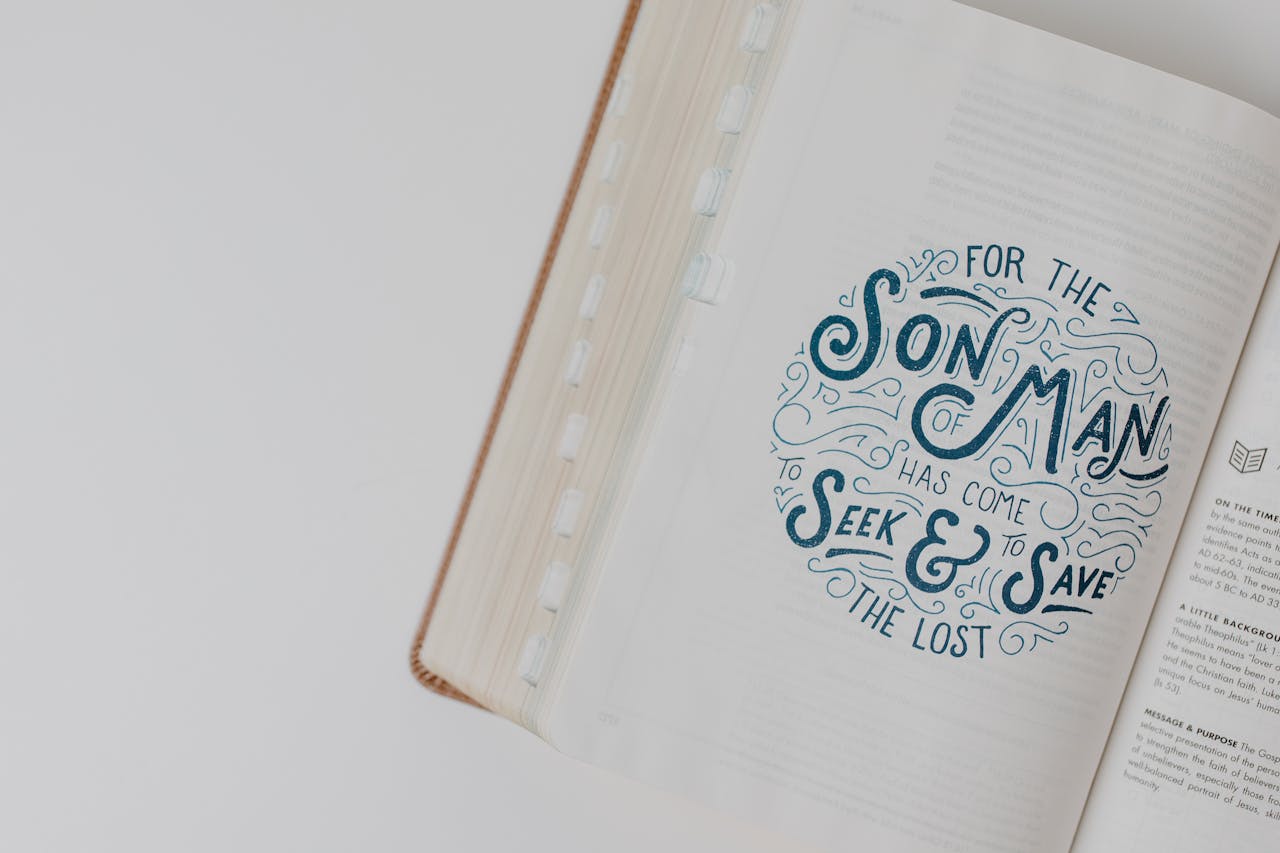 High-angle view of an open Bible with an inspirational scripture quote on a white surface.